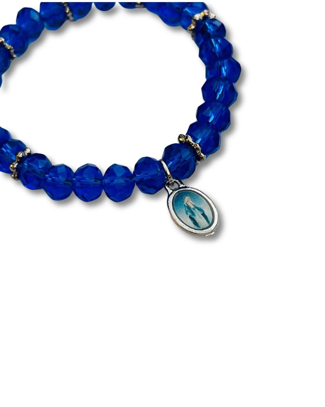 Detalhe da medalha de Nossa Senhora das Graças na pulseira de cristal azul. Close nas contas facetadas e no brilho do cristal.