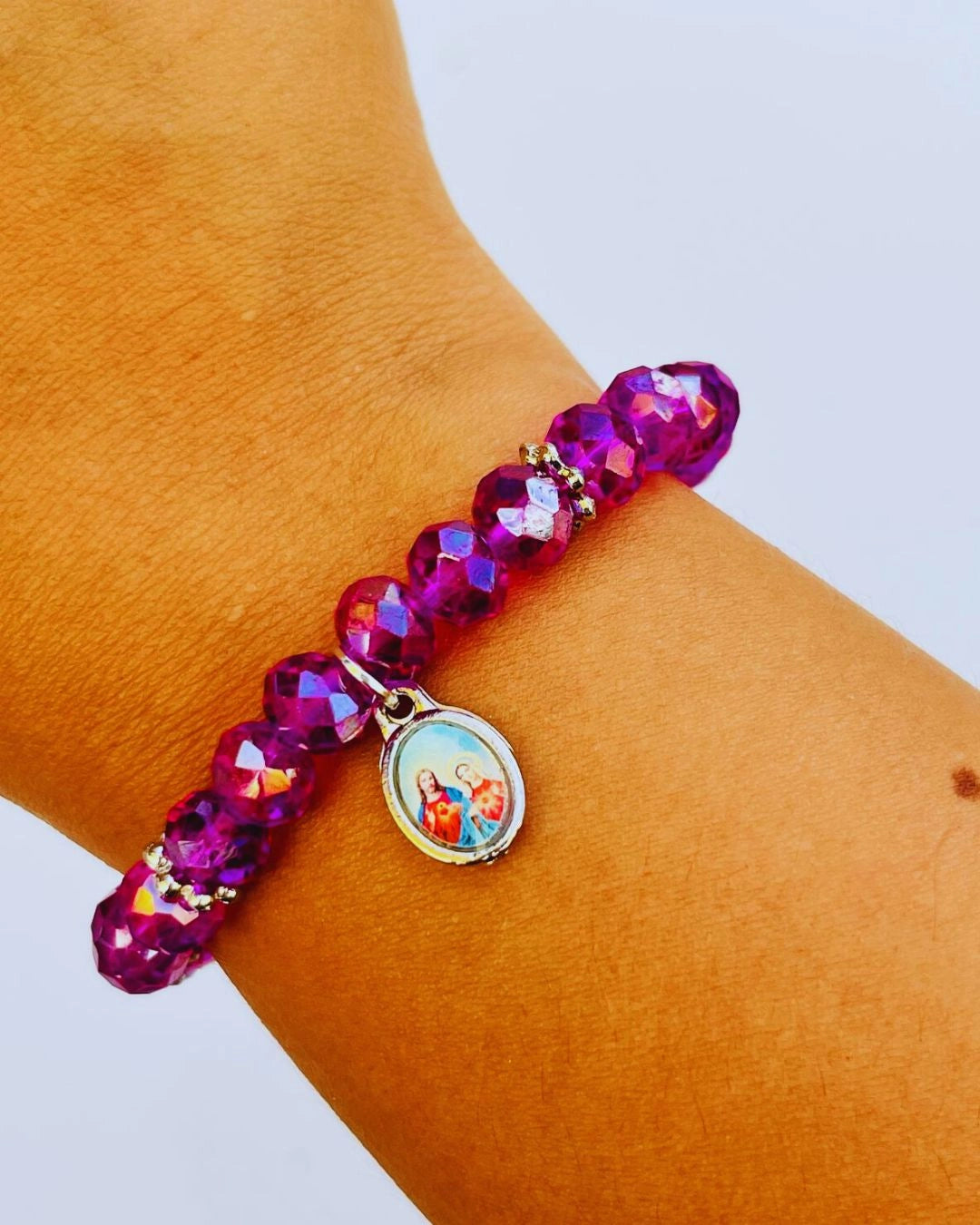 Pulseira de cristais roxos com medalha do Sagrado Coração de Jesus e Maria no pulso feminino – joia religiosa com brilho elegante.